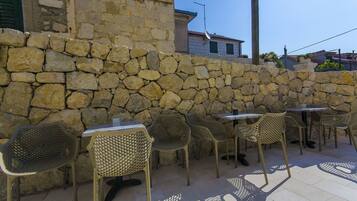 Outdoor seating with stone walls and metal chairs.