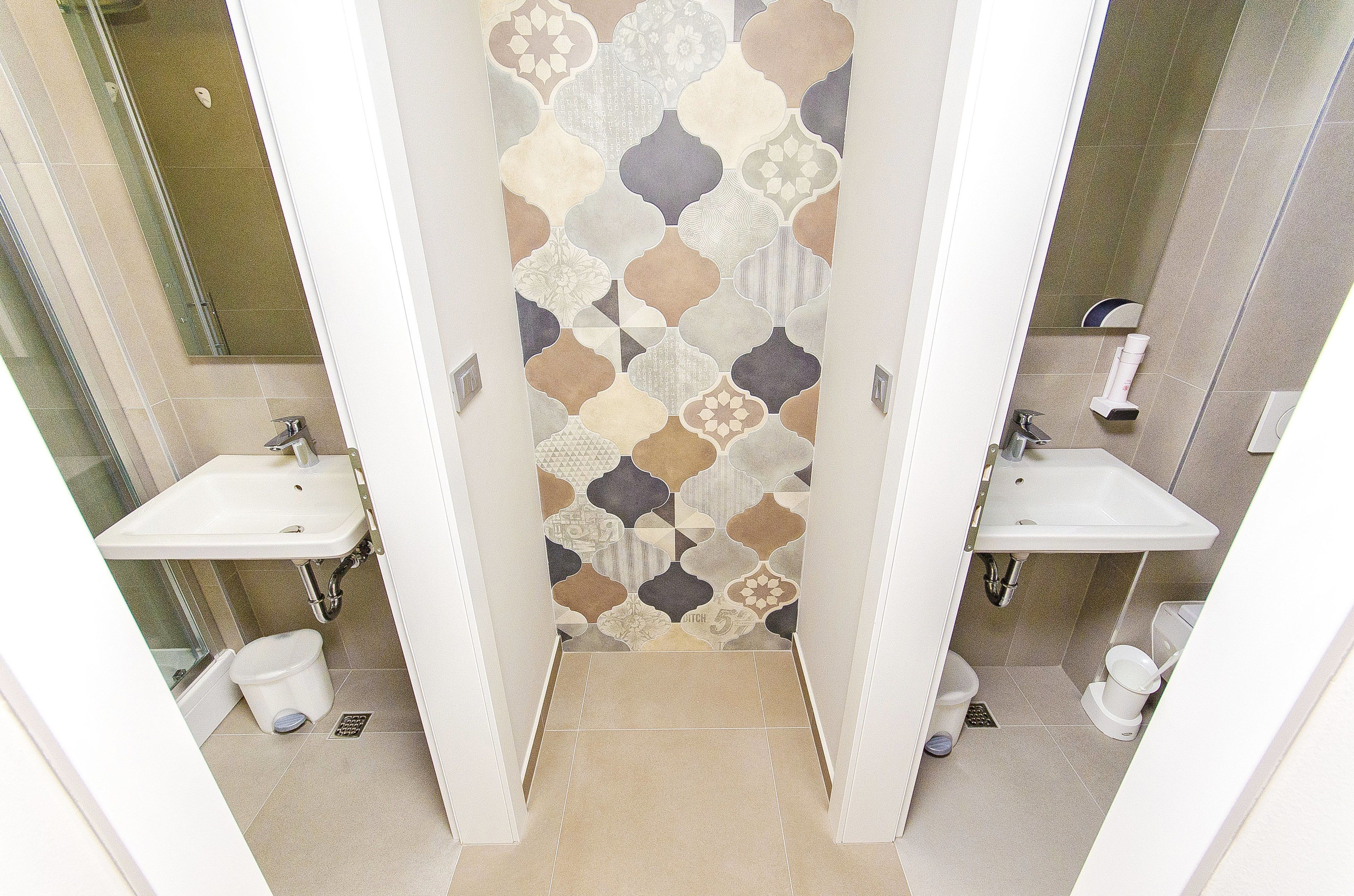 Une salle de bain avec deux lavabos, un mur à motifs et un sol carrelé.