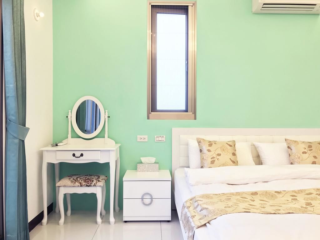 A bedroom with a bed, a nightstand with a mirror, a dresser, and a window.