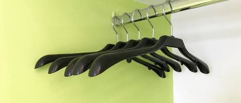 A metal curtain rod with black hangers against a lime green wall.