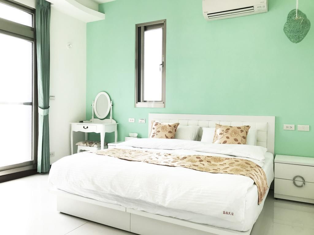 Un dormitorio con cama, mesita de noche, espejo, ventana y aire acondicionado.