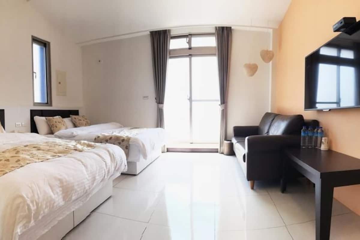 Een hotelkamer met twee bedden, een bureau, een televisie en een groot raam.