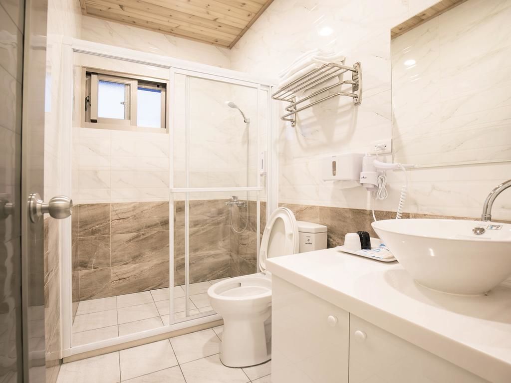 A modern bathroom with a glass-enclosed shower, a toilet, and a sink with a mirror.