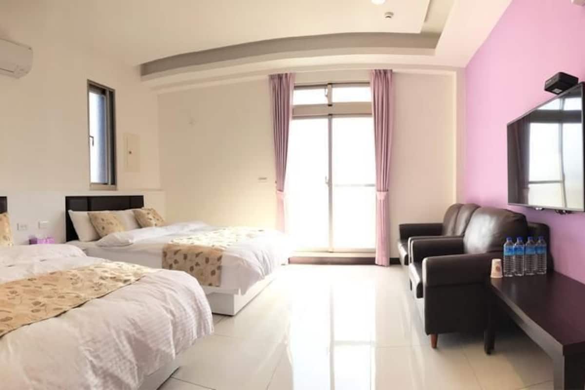 Hotelkamer met twee bedden, een bureau, een stoel, een televisie en een raam met gordijnen.