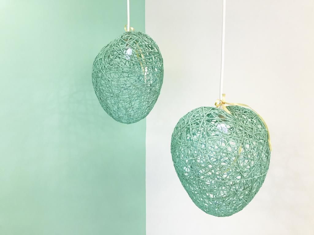 Deux luminaires suspendus de forme sphérique, de style filaire, sur un fond divisé en deux.