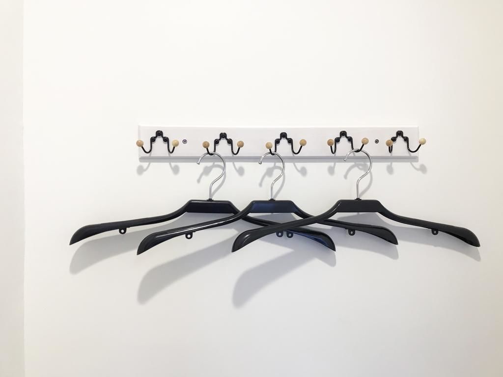 A wall-mounted coat rack with multiple hooks and a row of black hangers.