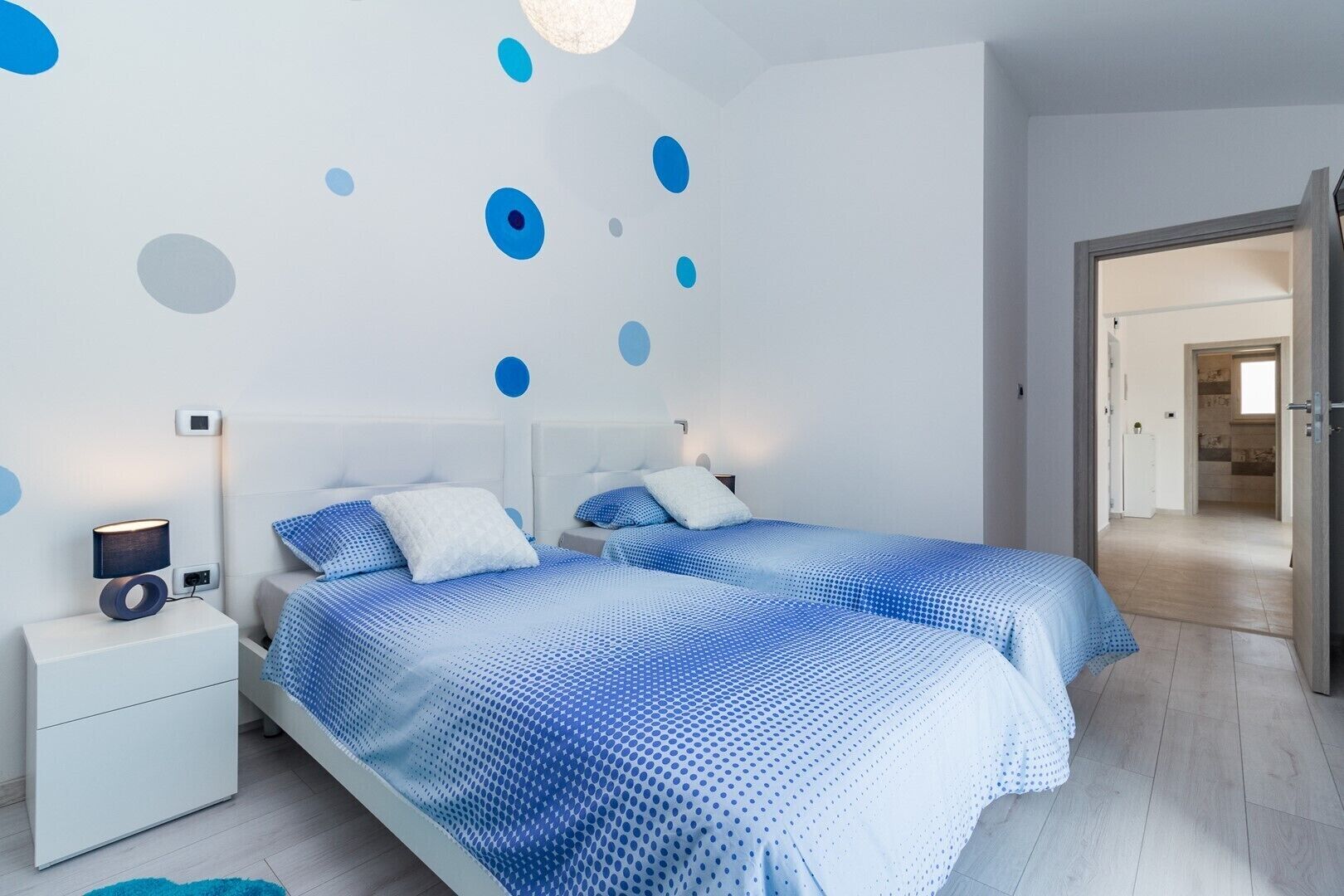 A bedroom with two beds, a nightstand, and a wall with circular patterns.