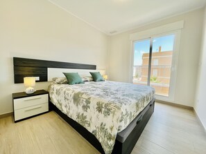 A bedroom with a bed, nightstands, and a window with a view of buildings.