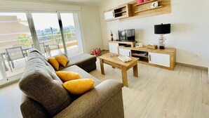 Un salon moderne avec un canapé, une table basse, un téléviseur et des étagères en bois.