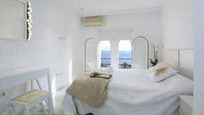 Une chambre à coucher avec un lit, un bureau et une grande fenêtre donnant sur la mer.