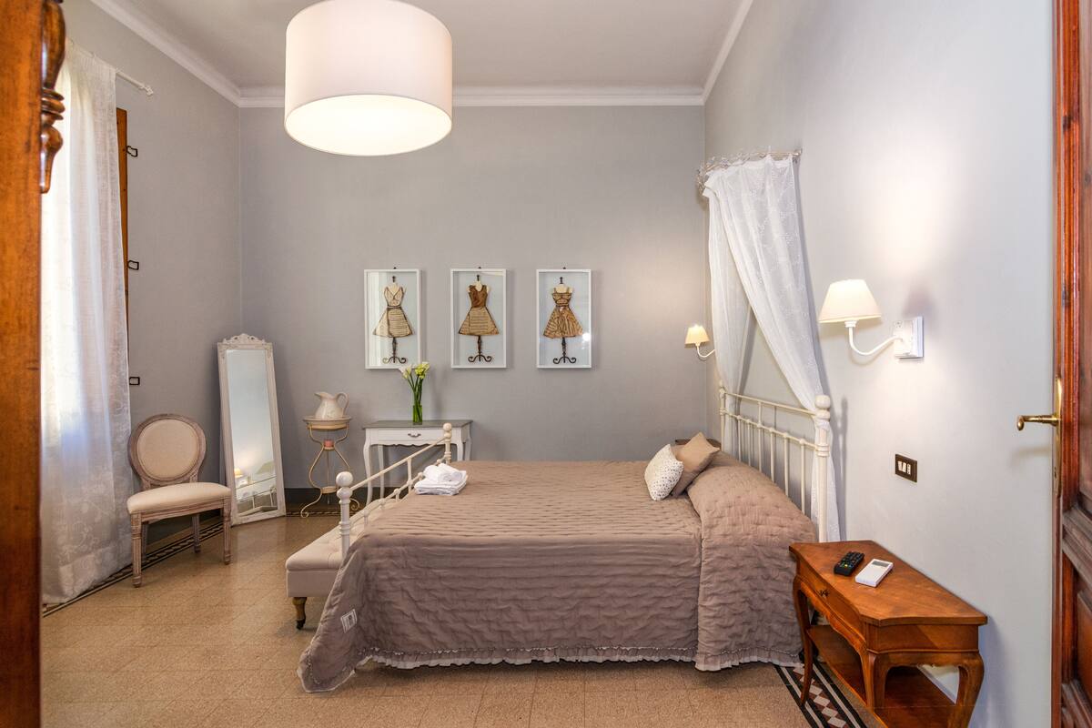 A bedroom with a bed, bedside table, chair, and wall-mounted lamp.