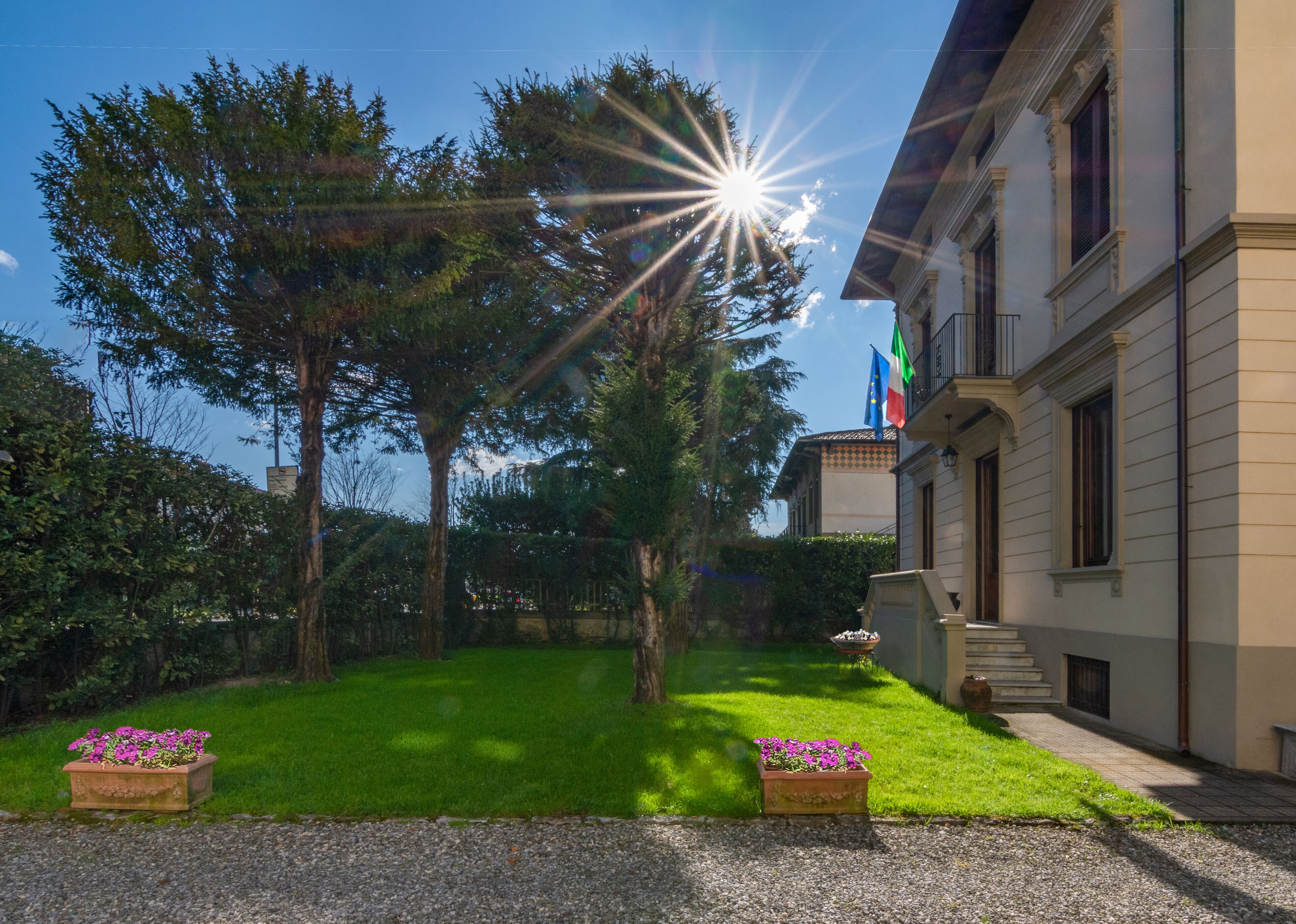 A building with a garden, a flag, and a clear sky.