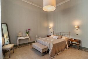 Una camera da letto con un letto, comodini, una scrivania, una sedia, una lampada e uno specchio.