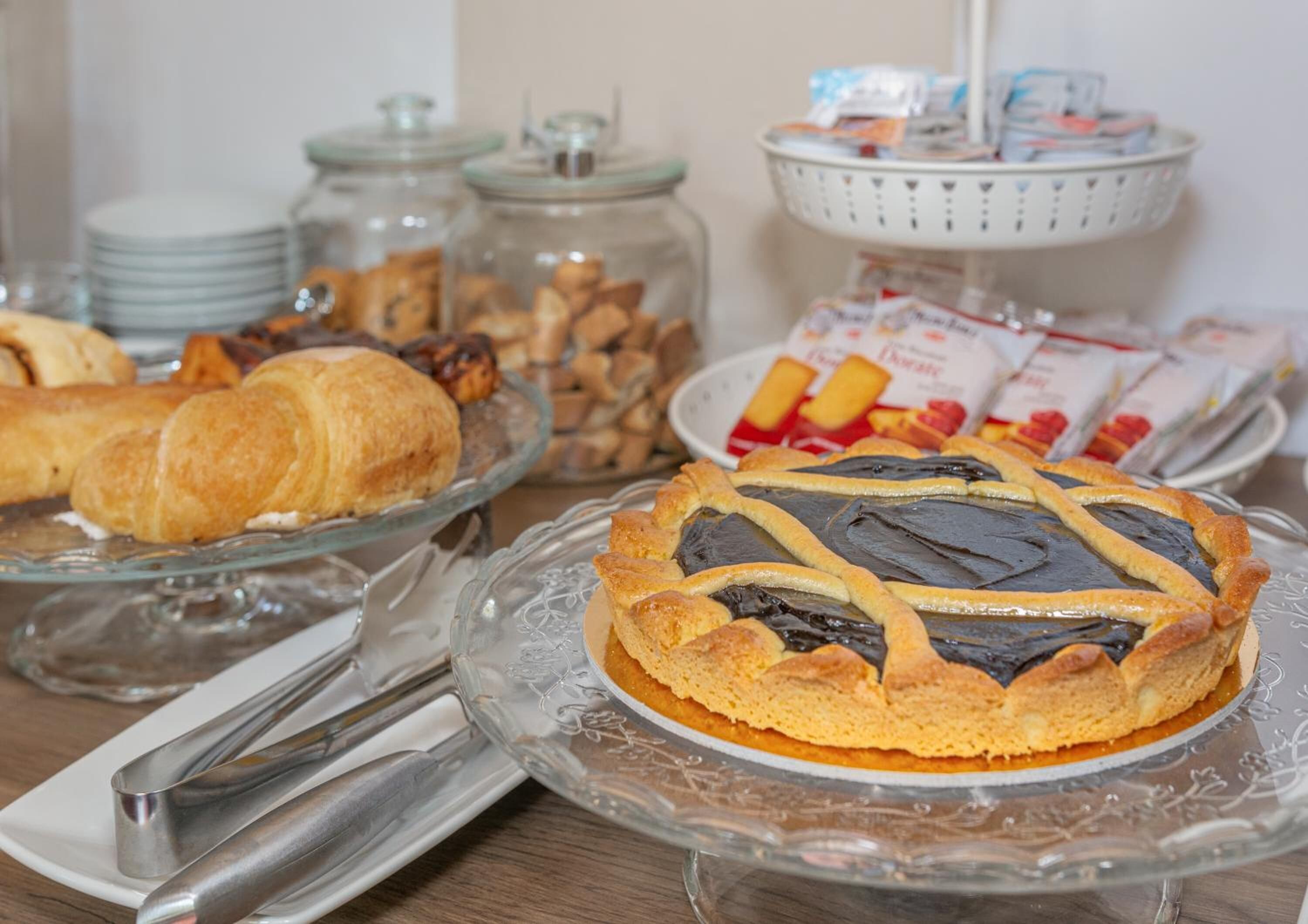 A buffet table with various pastries, a pie with a lattice crust, and condiments in jars.