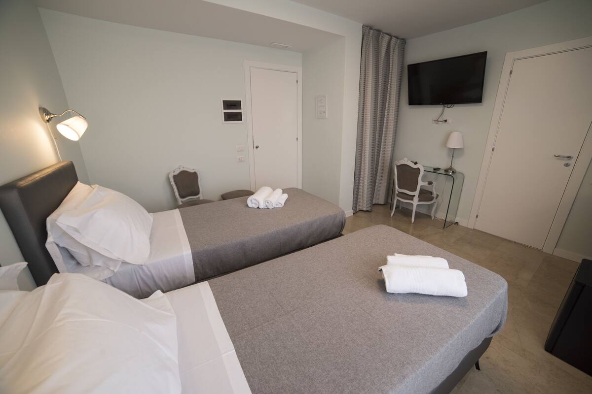 A hotel room with two beds, a TV, a desk, and a chair.