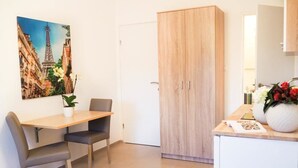A room with a wooden wardrobe, a dining table with two chairs, a potted plant, and a painting of the Eiffel Tower. - Villa Lotus (Pag)