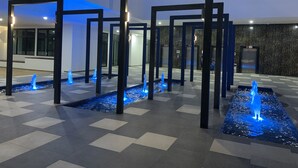 Een moderne binnenruimte met geometrische pilaren en waterpartijen.