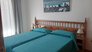Ein Schlafzimmer mit zwei Betten, einem Nachttisch, einer Lampe und einem Bild an der Wand.