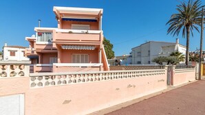 Ein mehrstöckiges Gebäude mit einer rosa Fassade, einem Balkon und einem befestigten Eingangsbereich.