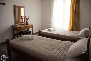 A hotel room with two beds, a wooden desk, a mirror, and a window with curtains. - Miss Soula by Estia (Malevizi)