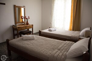 Una habitación de hotel con dos camas, un escritorio de madera, un espejo y una ventana con cortinas.