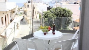 Un balcon avec une table dressée pour deux personnes, agrémentée d’un panier de fruits, d’une bouteille de vin et de deux verres.