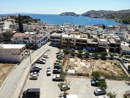 Un pueblo costero con edificios residenciales, un estacionamiento y vista al mar.