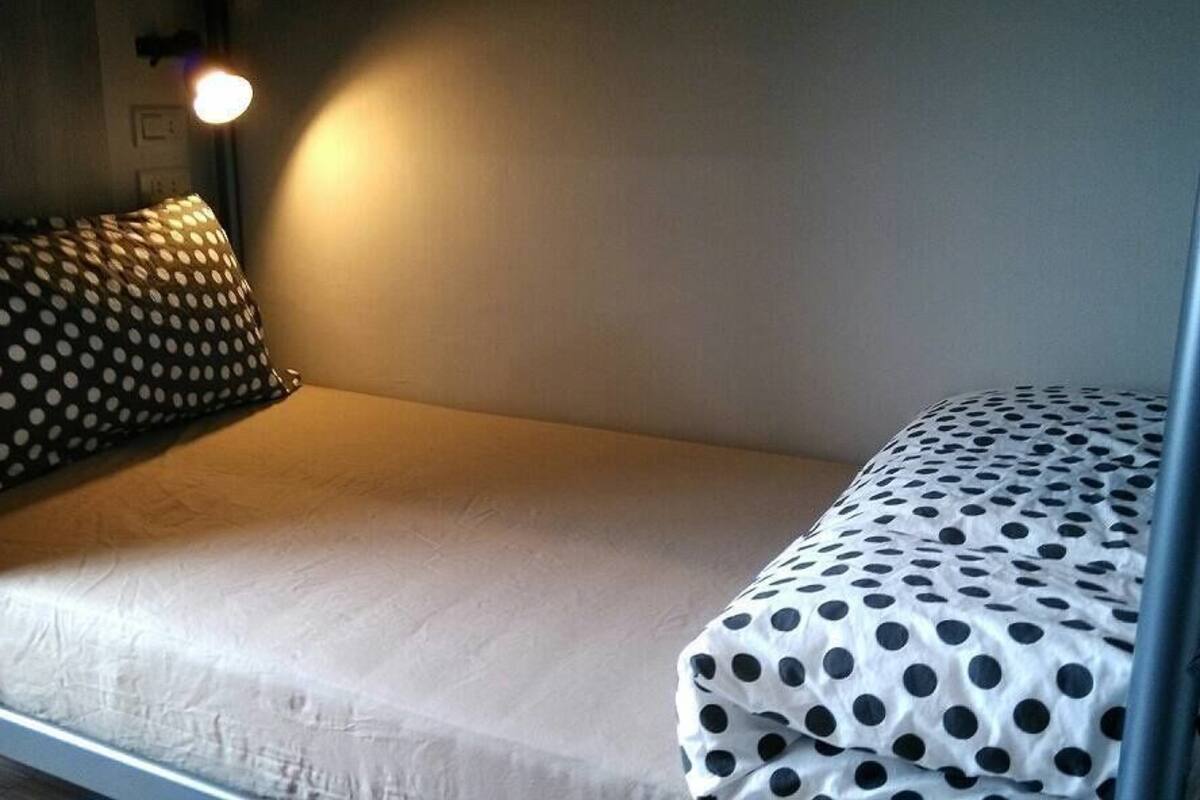 A single bed with a white mattress and a polka dot duvet.