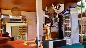 A spacious living area with wicker furniture, a refrigerator, and a view of the outdoors. - Bella Athena Garden (El Nido)