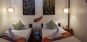 Two twin beds with decorative swan pillows, a small bedside table, and a wall-mounted light fixture.