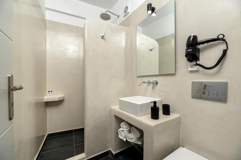A modern bathroom with a shower, a sink, a hairdryer, and a towel rack.