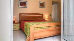 Ein Schlafzimmer mit einem hölzernen Bett, einem Nachttisch, einer Lampe und zwei gerahmten Bildern an der Wand.