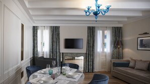 Un coin repas avec une table ronde dressée pour quatre personnes, un canapé et un téléviseur en arrière-plan.