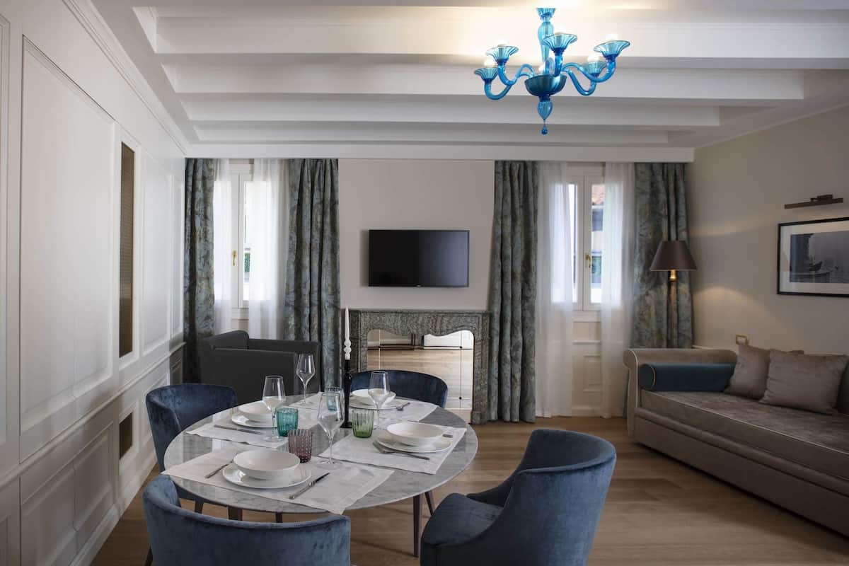 Un área de comedor con una mesa redonda para cuatro personas, un sofá y un televisor al fondo.