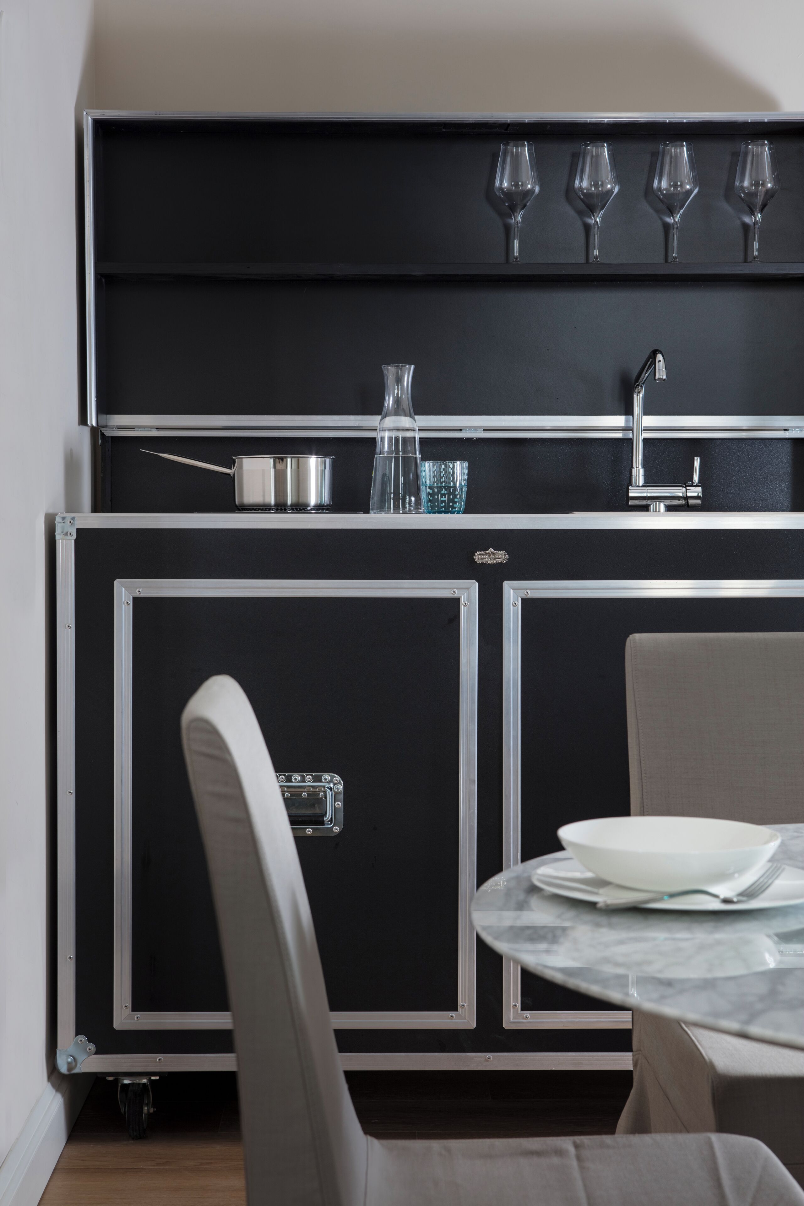 A compact kitchen with a black countertop, a sink, and a dining area with a table and chairs.