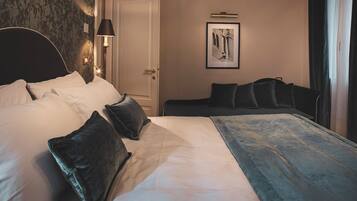 Ein Hotelzimmer mit einem großen Bett, einem Nachttisch mit Lampe, einem gerahmten Bild an der Wand und einer Tür.