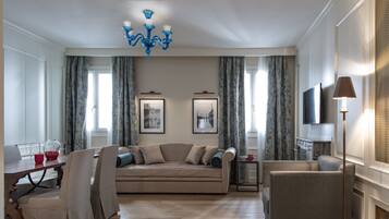A living room with a sofa, chairs, a TV, and a chandelier.
