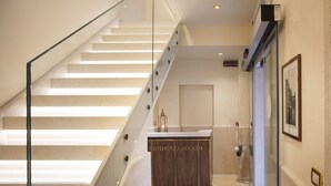 Un intérieur d’hôtel moderne avec un escalier en verre menant à un comptoir d’accueil portant l’inscription « RESIDENZA DUCATO ».