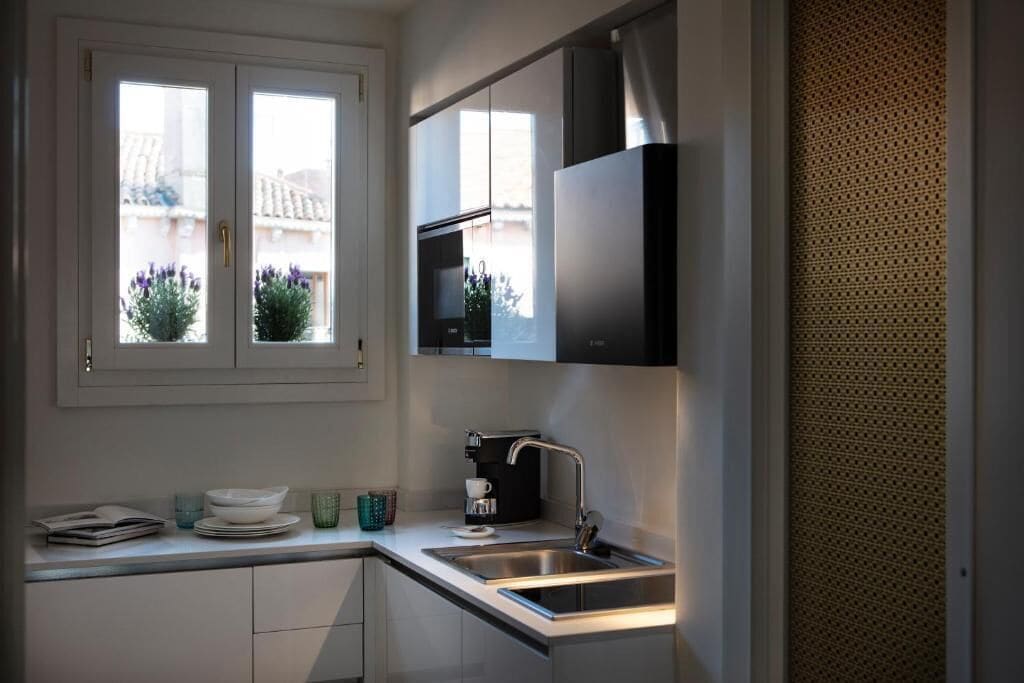 Una cocina moderna con horno empotrado, cafetera y pileta.