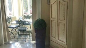 Un suelo a cuadros, una zona de comedor con sillas y una mesa, y un mueble con una planta encima.