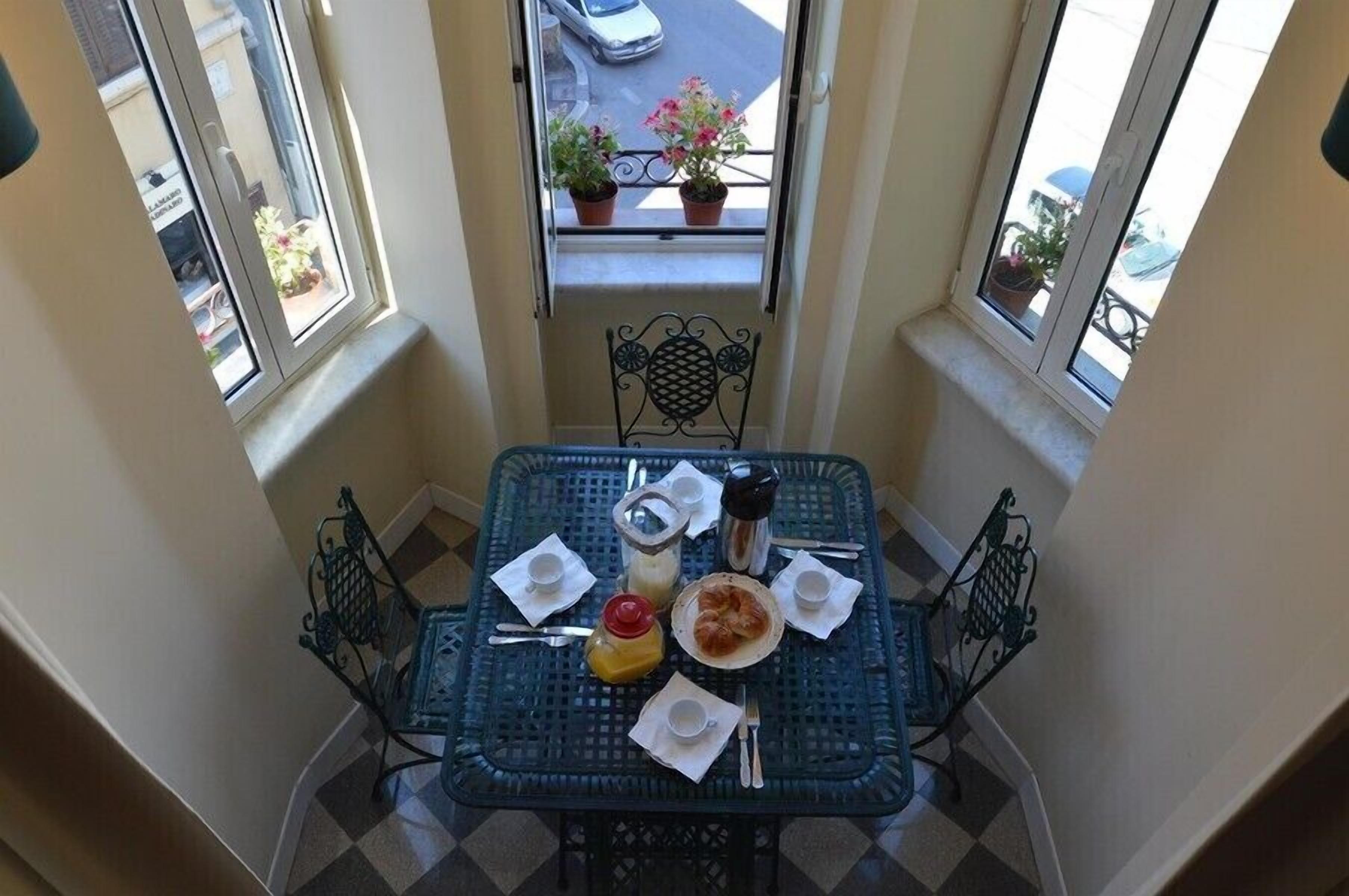 A dining table with a checkered tablecloth, set with plates, cups, and cutlery.