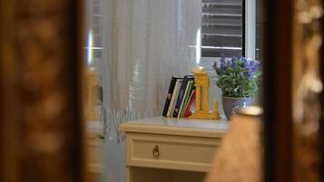 Un bureau avec une plante et des livres, une fenêtre avec des stores et un rideau.