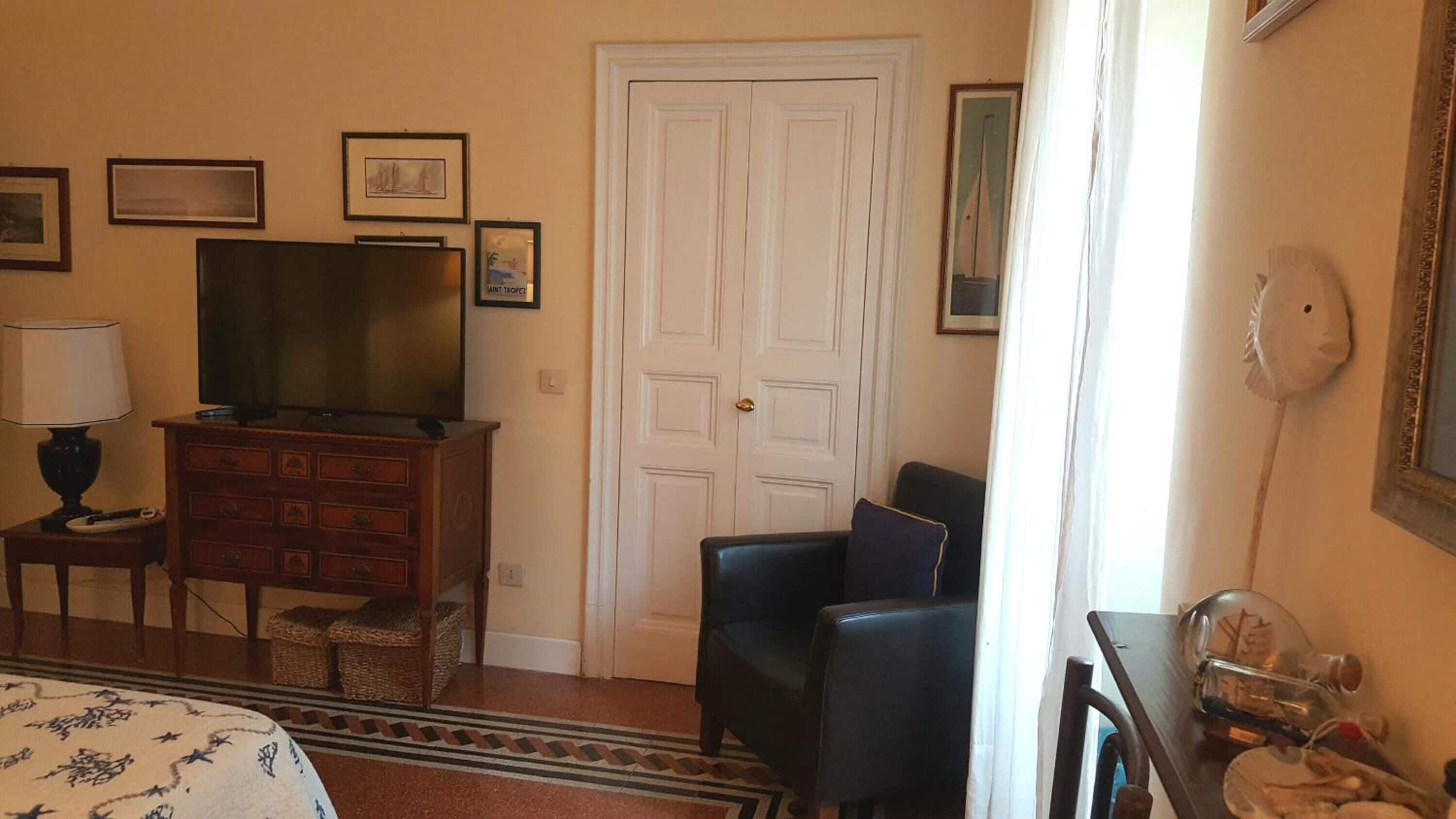 A hotel room with a bed, a dresser, a television, a chair, and a door.