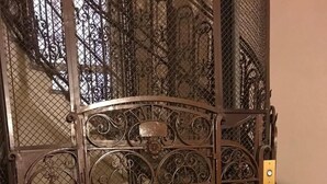 Una reja de hierro forjado con diseños intrincados, que da acceso a una escalera.