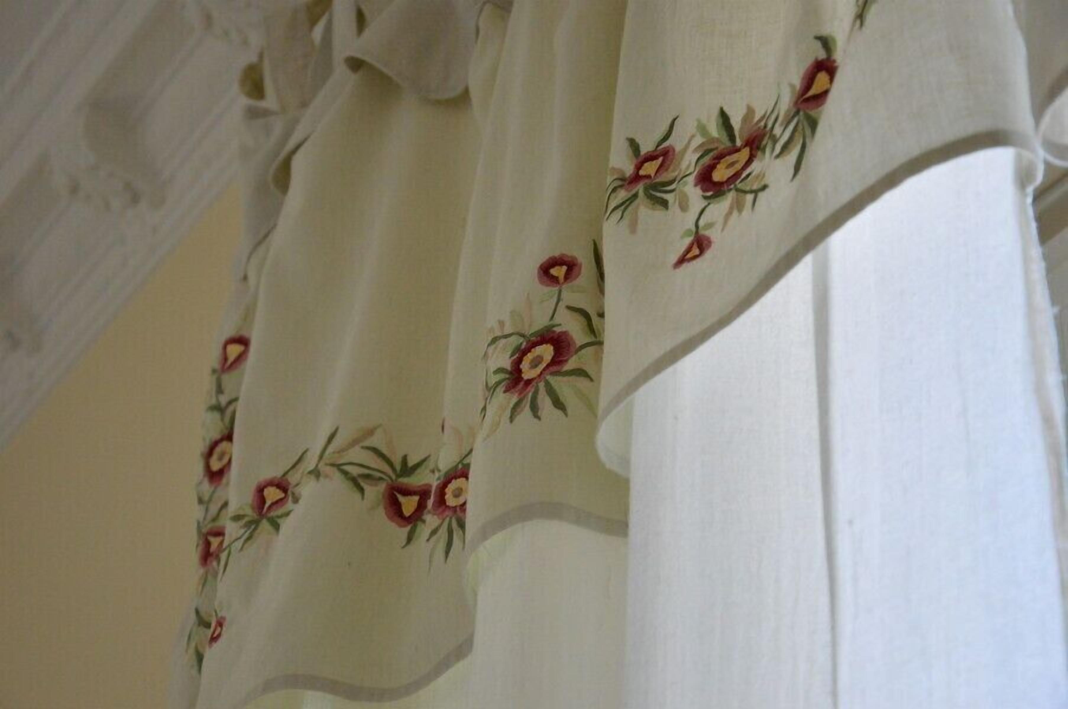 A white curtain with floral embroidery.