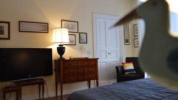 A hotel room with a bed, a TV, a dresser, and a door.