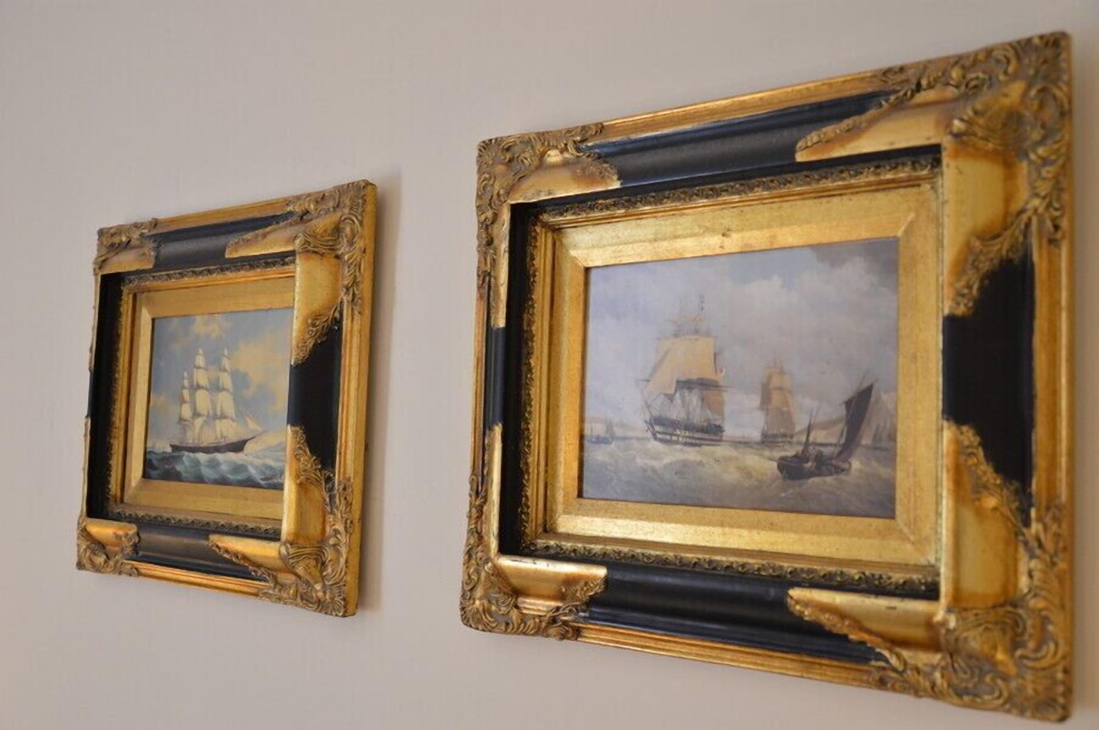 Two framed paintings of sailing ships on a wall.