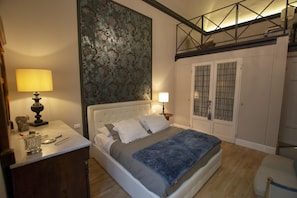 A bedroom with a bed, bedside tables, a large decorative wall, and a wardrobe.