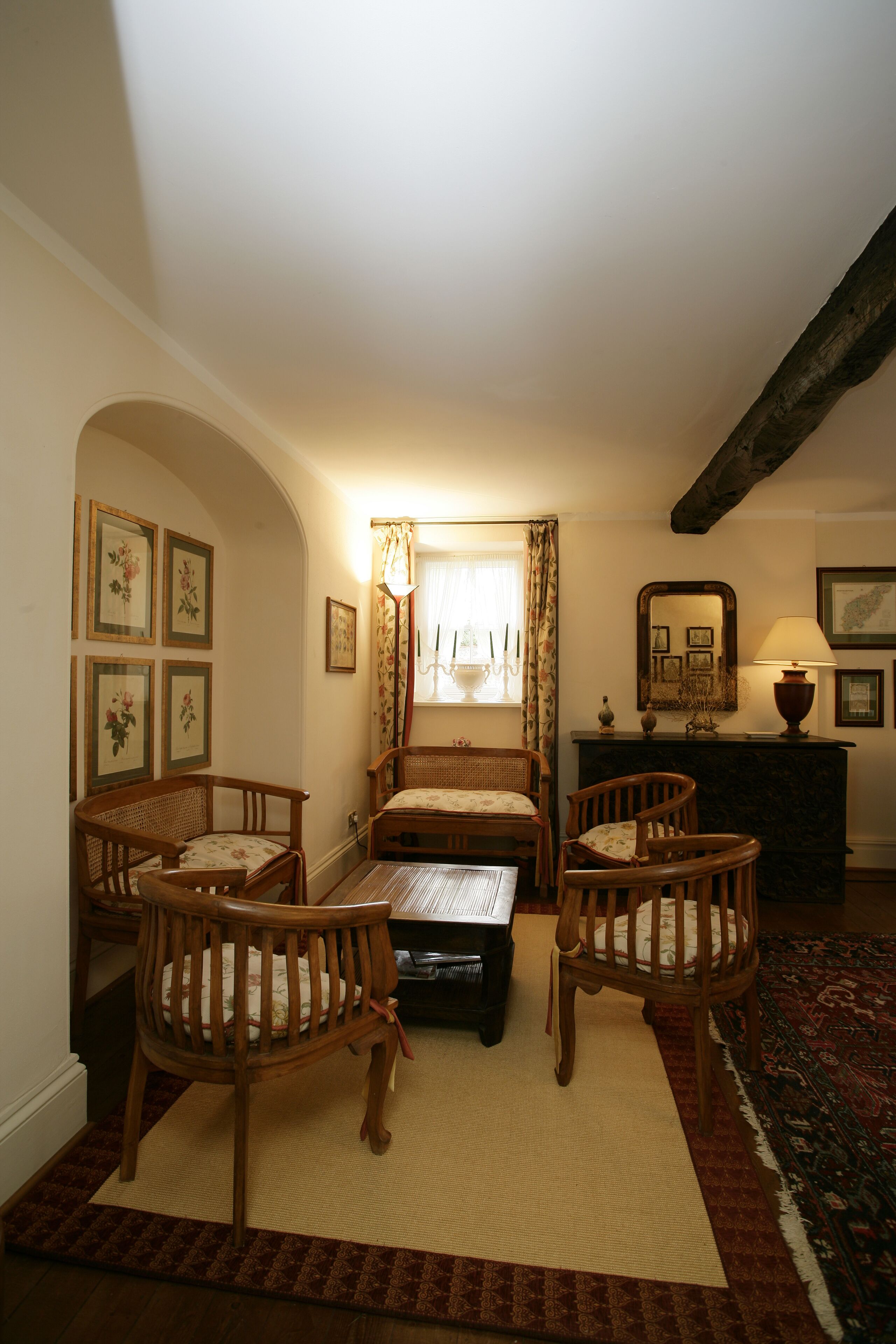 Una habitación acogedora con una cama, dos sillas de madera, una mesita y una alfombra.