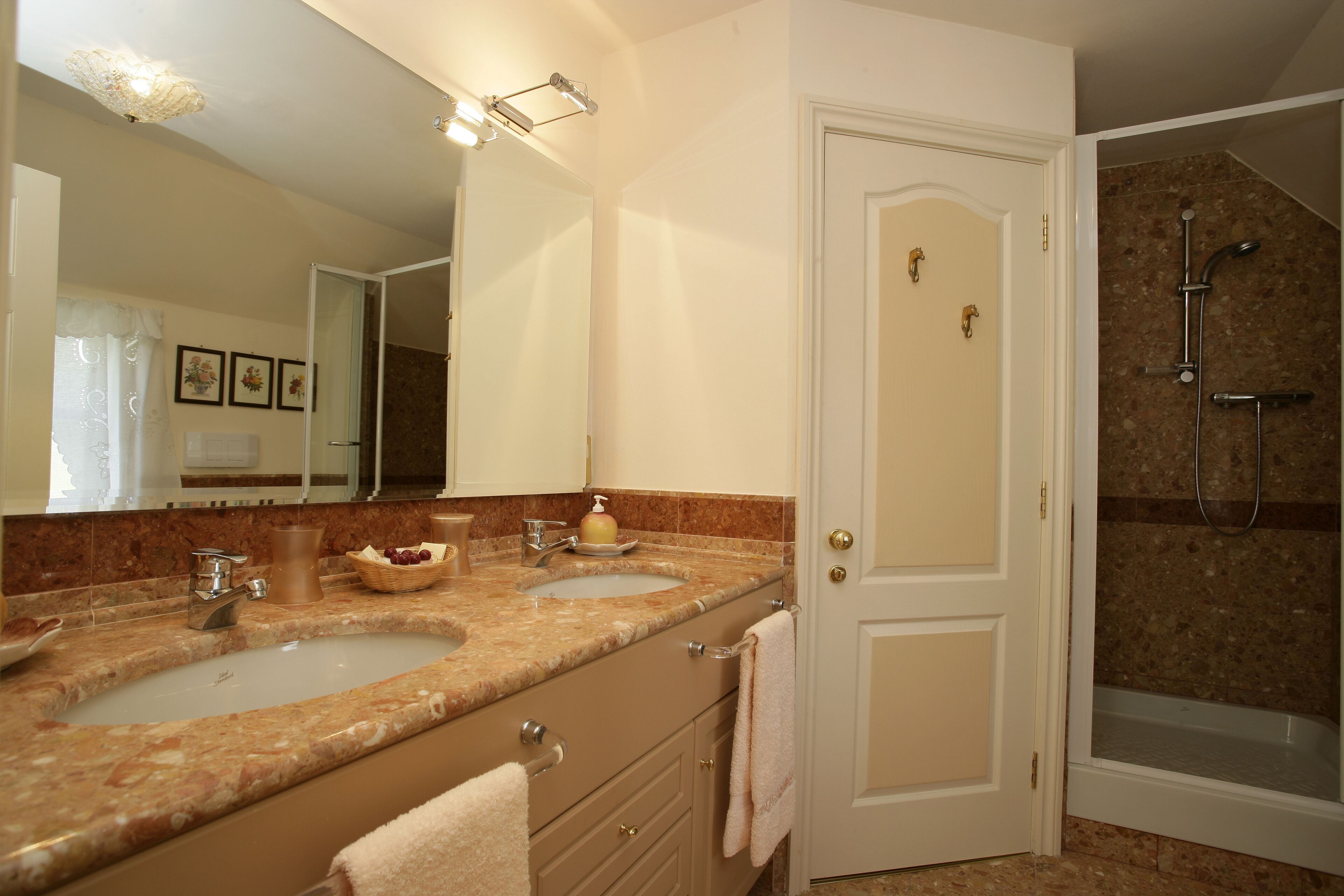 A bathroom with two sinks, a mirror, and a shower.